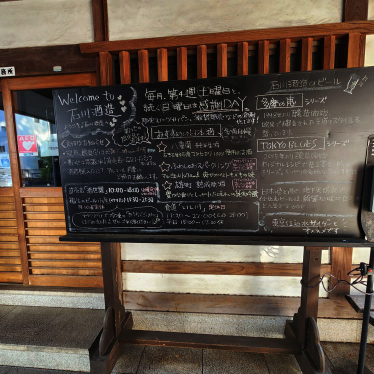 石川酒造で扱っている商品（日本酒やクラフトビール）の説明や敷地内店舗の営業時間などを黒板に手書きで書かれた案内の写真